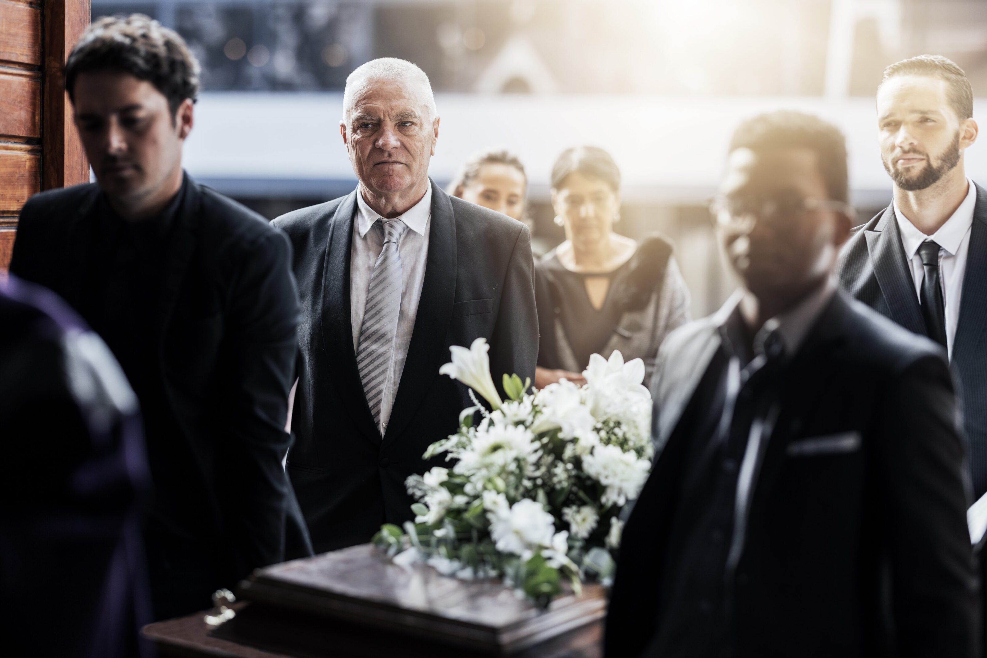 Pallbearers carrying a casket with flowers.