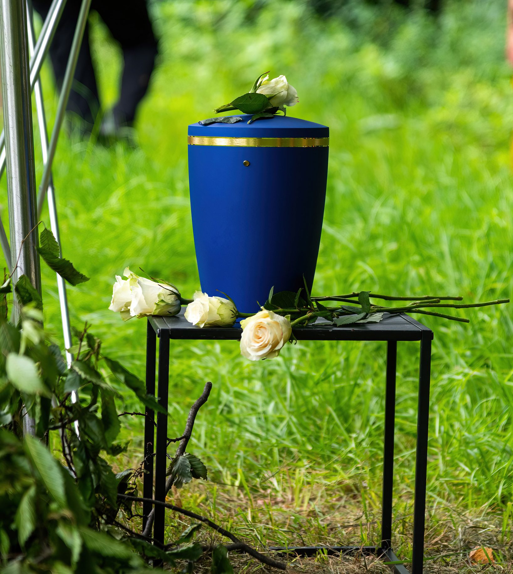 one blue urn and white roses prepared for funeral at a green field